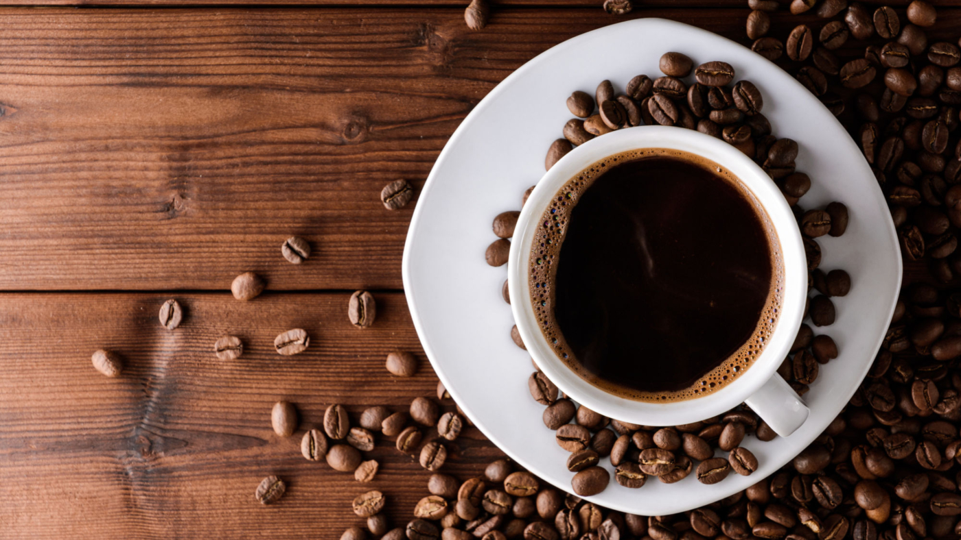 Coffee cup and beans on wooden table. Top view.